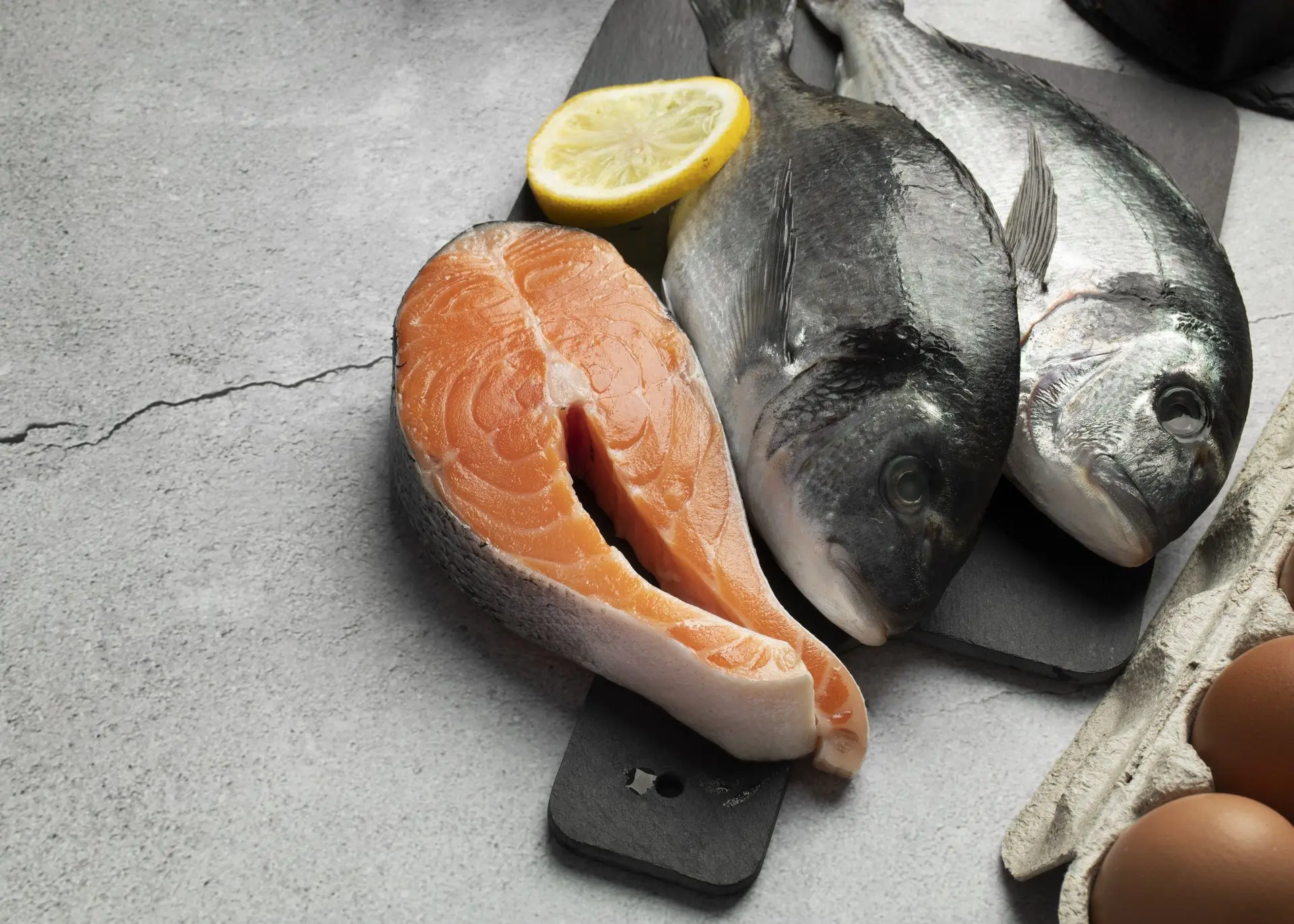 Omega-3: clave para reducir la inflamación en articulaciones y músculos Filete de salmón fresco junto a limón amarillo, fuente rica en Omega-3 para la salud articular y muscular.