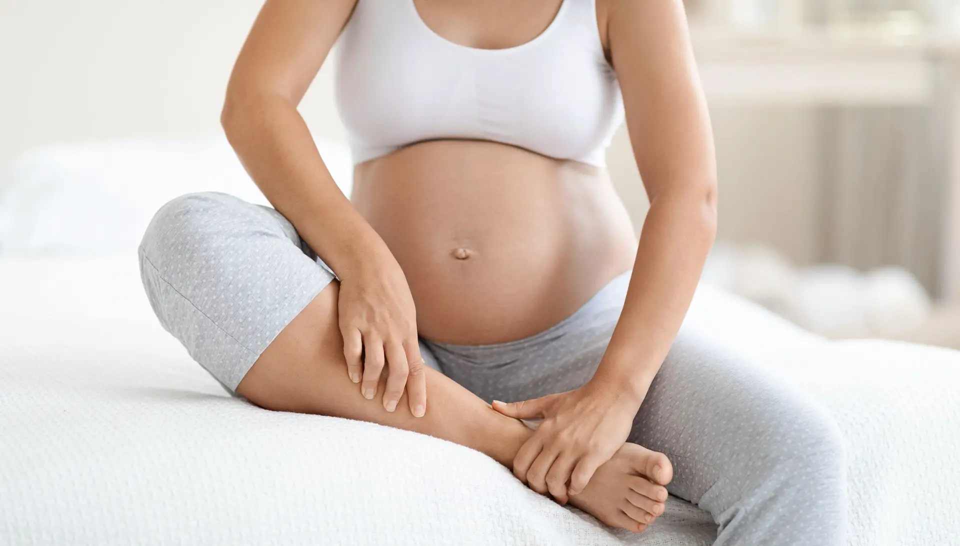 Mujer embarazada sentada masajeando sus pies